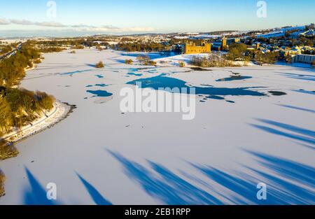 Winterszene Schottland: Luftaufnahme des Sonnenuntergangs auf Linlithgow Palace und Linlithgow Loch. Stockfoto