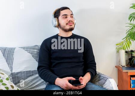 Junge kaukasische Mann entspannt beim Hören von Musik mit einem Kabellose Kopfhörer Stockfoto