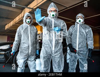 Gesundheitshelfer zeigt Stop-Geste. Ein Team von Mitarbeitern im Gesundheitswesen, die Hazmat-Anzüge tragen, arbeitet zusammen, um einen Ausbruch in der Stadt zu kontrollieren Stockfoto