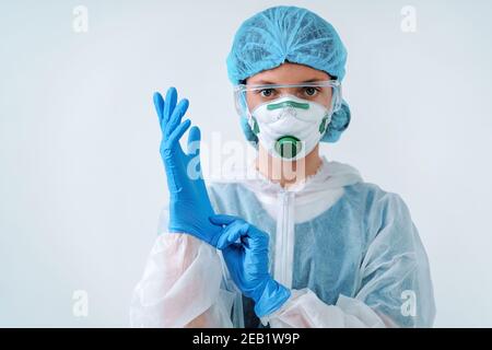 Gesundheitsarbeiter in Schutzanzug und medizinische Maske zieht Handschuhe an. Gesundheitskonzept. Stockfoto