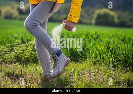 Frau Wanderer sprühen Insektenschutzmittel gegen Zecke auf ihre Beine und Stiefel. Tourist Anwendung Mückenschutz Stockfoto