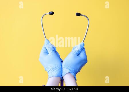 Die Hände des Arztes in Handschuhen halten das Stethoskop in der Nähe Stockfoto