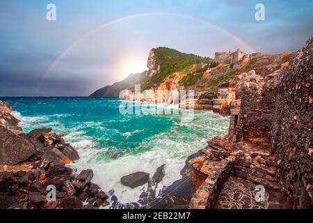 Regenbogen auf Portovenere (porto venere) Schloss Doria in Ligurien Italien in der Nähe von cinque terre. Wellen brechen an felsiger Küste Stockfoto