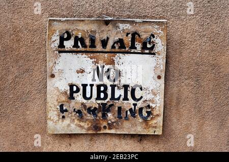 Ein verwittertes und beflecktes Schild ohne Parkplatzschild an einer lehmwand in Santa Fe, New Mexico. Stockfoto