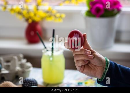 Frau hält Osterei. Dekoration und Vorbereitung für religiöse Urlaub zu Hause. Frühlingsblumen als Dekoration Stockfoto
