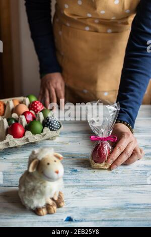 Frau hält eingewickelte osterei als Geschenk für Ostern Feiertagsfeier. Dekoration auf dem Tisch Stockfoto