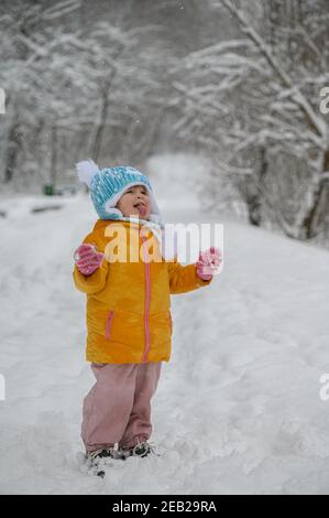 Kleines Mädchen fangen Schneeflocken auf der Zunge Stockfoto