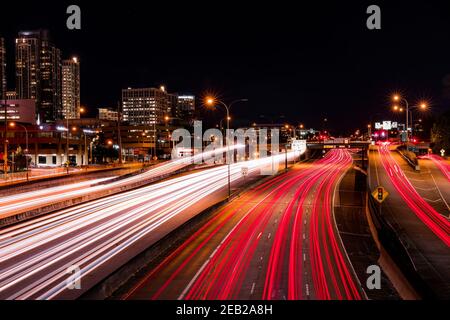 Langzeitbelichtung über einer Autobahn im Dunkeln der Nacht während der Hauptverkehrszeit. Stadtbild Hintergrund. Stockfoto