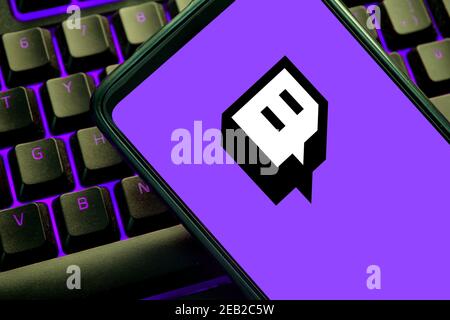 Twitch-Symbol auf einem Handybildschirm auf einer violett beleuchteten Gaming-Tastatur. Streaming-Website für Videospiele Stockfoto