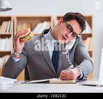 Die hungrigen lustig Geschäftsmann Essen der Trödelnahrung Sandwich Stockfoto