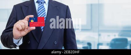 Zugeschnittenes Bild des Geschäftsmannes, der eine Plastikkreditkarte mit bedruckter Flagge von Westsamoa hält. Hintergrund unscharf. Stockfoto