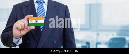 Zugeschnittenes Bild von Geschäftsmann hält Kunststoff-Kreditkarte mit bedruckter Flagge von Indien. Hintergrund unscharf. Stockfoto