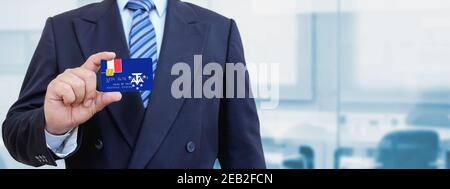 Zugeschnittenes Bild eines Geschäftsmannes, der eine Plastikkarte mit bedruckter Flagge der südlichen und antarktischen Länder hält. Hintergrund unscharf. Stockfoto