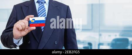 Zugeschnittenes Bild des Geschäftsmannes mit Plastikkreditkarte mit bedruckter Flagge Sloweniens. Hintergrund unscharf. Stockfoto