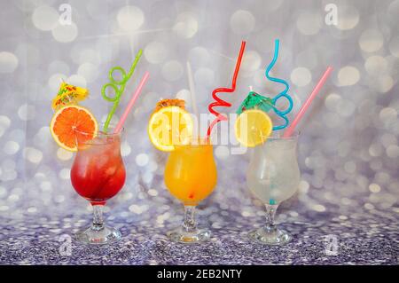Drei Gläser mit Zitrusfrüchten mit Eis und Scheiben, Orange, Zitrone und Grapefruit auf grauem, glänzendem Hintergrund. Nahaufnahme. Stockfoto