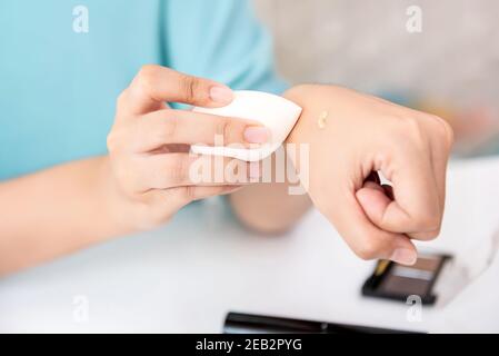 Nahaufnahme der weiblichen Hand mit einer weißen Schönheit Mixerschwamm zum Abwischen von Flüssigmake auf der Hand Stockfoto