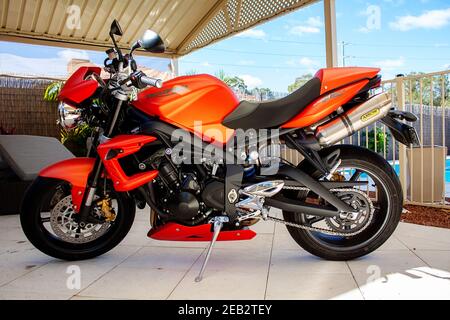 2010 Triumph Street Triple R orange Motorrad, geparkt auf Pflaster unter einer Terrasse Stockfoto