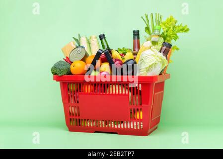 Farbenfrohe Lebensmittel und Lebensmittel, darunter frisches Obst und Gemüse Roter Supermarkt Plastikkorb Stockfoto