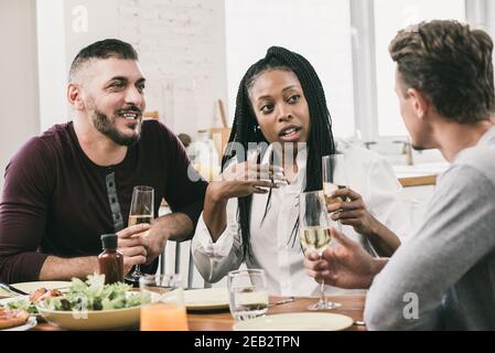 Gruppe von verschiedenen Nachbarn, die Unterhaltung in der sozialen Versammlung Partei Während Sie ein Glas Weißwein trinken Stockfoto