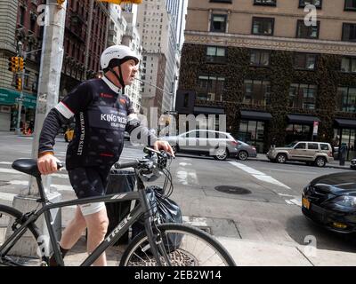 Ein älterer Straßenfahrradfahrer läuft sein Fahrrad auf dem Bürgersteig in Manhattan New York. Stockfoto