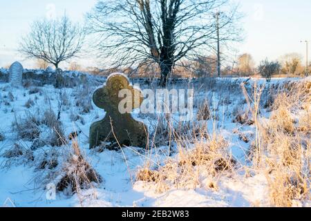 Grabstein im Kirchhof St. Peter und St. Paul im Schnee. Long Compton, Warwickshire, England Stockfoto