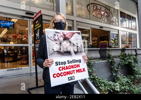 Los Angeles, Usa. Februar 2021, 11th. PETA-Aktivist hält ein Plakat während eines Protestes gegen Thailands Chaokoh-Marke, weil sie angeblich Affen dazu gezwungen haben, auf Bäume zu klettern, Kokosnüsse zu sammeln und sie unter grausamen Bedingungen zu halten. Große US-Einzelhändler wie Costco und Target stoppten den Verkauf von Chaokoh Kokosmilch über Vorwürfe der Zwangsarbeit von Affen. Kredit: SOPA Images Limited/Alamy Live Nachrichten Stockfoto