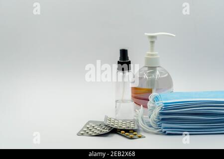 Weiße medizinische Masken und Atemschutzgeräte, Händedesinfektionsmittel und Medikamente auf weißem Hintergrund. Gesichtsmasken Schutz KN95 oder N95 und chirurgische Masken für zu schützen Stockfoto