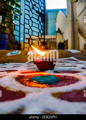 Rangoli mit Öllampen reiche Farben auf der glückverheißenden Anlass der indischen Festivals gezeichnet. Diya Öllampen beleuchtet auf bunten Rrangoli. Stockfoto