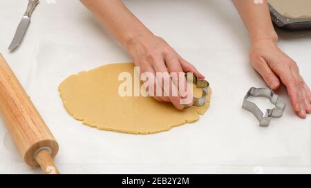 Plätzchenteig und Plätzchenausstecher schließen sich auf dem Küchentisch an. Rezept für Kekse in Form von Blumen Stockfoto