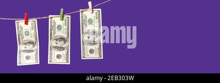 Amerikanische Dollar werden auf einem Seil auf einem violetten Hintergrund mit Platz für Text getrocknet. Stockfoto