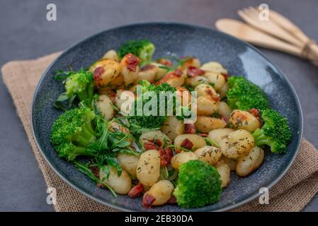 Gebratene italienische Gnocchi mit Speck und Brokkoli Stockfoto