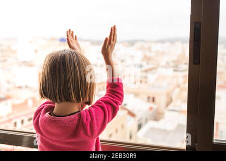 Blonde kleine Mädchen applaudierenden medizinischen Personal aus ihrem Fenster während Die Coronavirus-Pandemie Stockfoto
