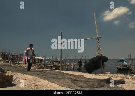 Ein Mann, der am Fischerstrand von Kamal Muara, einem Küstendorf, läuft, wo der Lebensunterhalt hauptsächlich auf Fischerei und Meereslebensmittelproduktion in Jakarta, Indonesien, angewiesen ist. Stockfoto