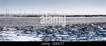 Windmühlenpark Westermeerwind im IJsselmeer, dem größten Offshore-Windpark der Niederlande. Winterszene mit Schnee, Sonne und blauem Himmel. Widescree Stockfoto