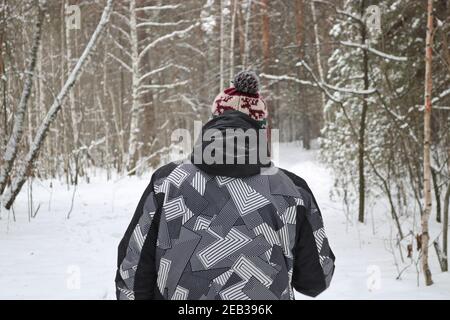 Der Mensch geht in den Wintersport - nordic Walking, Spaziergänge mit Stöcken durch einen verschneiten Wald. Aktive Menschen in der Natur. Stockfoto