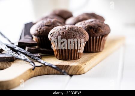 Schokoladen-Muffins. Süße dunkle Cupcakes mit Schokolade und Vanilleschoten auf Schneidebrett. Stockfoto