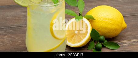 Erfrischender Limonadensaft im Glas mit Zitronen auf Holztisch Hintergrund, Bannergröße Stockfoto