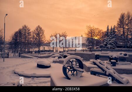 Die Ansicht der Museumsausstellung von Bergbaumaschinen unter Schnee mit dem Lisya (Lisaya) Berg im Hintergrund bei Sonnenuntergang Licht. Nischni Tagil. Russland Stockfoto