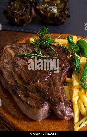 Gegrilltes Ribeye-Steak mit Rosmarin auf einem Holztisch Stockfoto