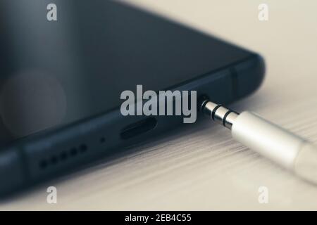 Anschluss 3,5 mm Audiobuchse an ein schwarzes Mobiltelefon. Stockfoto