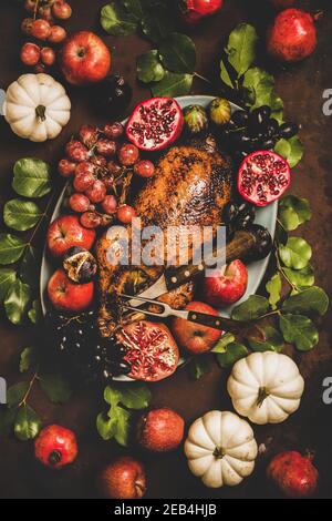 Herbst Thanksgiving, Friendsgiving, Familienfest Festessen. Flacher Herbsttisch mit gebratener Ente in saisonalen Früchten, verziert mit Kürbissen und Blättern auf rostigem Hintergrund Stockfoto