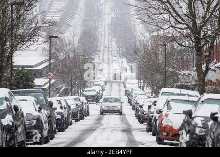 London, Großbritannien - 9. Februar 2021 - EIN Auto auf einer Straße unter Schneesturm in Crouch End, widrige Fahrbedingungen Stockfoto