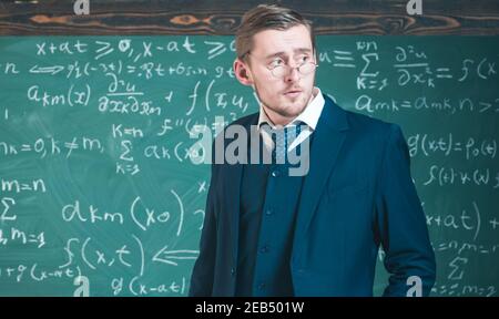 Junge Lehrerin in Brille posiert im Klassenzimmer. Elite-Bildungskonzept. Stockfoto