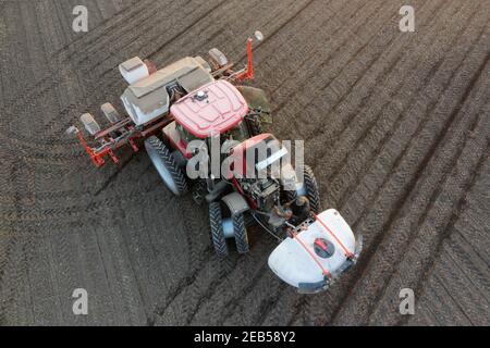 Ein moderner Traktor sät das Feld und verwendet lösliche Düngemittel und Pestizide. Stockfoto