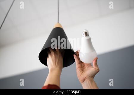 Frau, die die kaputte Glühlampe in LED umwandelt Stockfoto