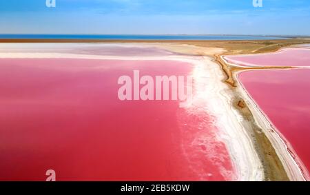 Blick von oben auf einen rosa See. Das schmale Ufer, das den See und die Meeresbucht trennt. Rosa See mit hohem Salzgehalt. Stockfoto