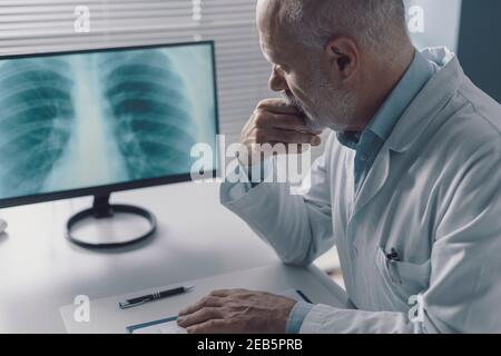 Fokussierter Arzt, der ein Röntgenbild des Brustkorbs eines Patienten überprüft Auf dem Computerbildschirm Stockfoto