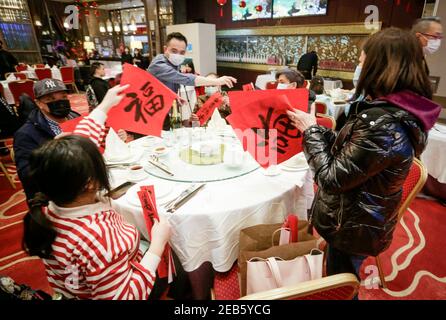 Richmond, Kanada. Februar 2021, 11th. Die Menschen tauschen sich während des Abendessens zum chinesischen Neujahrsfest in einem Restaurant in Richmond, British Columbia, Kanada, am 11. Februar 2021 über chinesische Fu-Muster aus, was Glück bedeutet. Quelle: Liang Sen/Xinhua/Alamy Live News Stockfoto