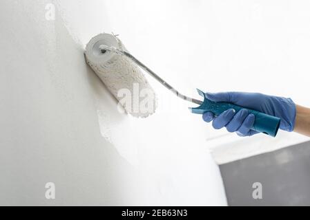 Nahaufnahme einer Hand Malerei Wand weiß mit einer Rolle Stockfoto