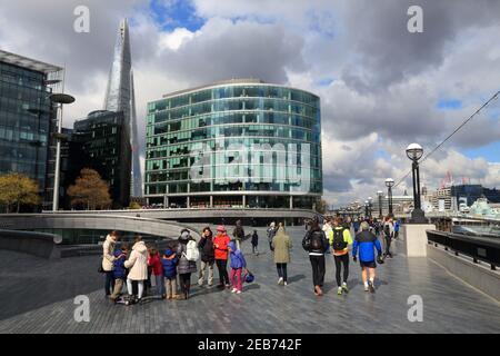 LONDON, Großbritannien - 23. APRIL 2016: Die Menschen laufen am Ufer der Themse in London entlang. London ist die bevölkerungsreichste Stadt und Metropolregion des Vereinigten Königreichs mit Stockfoto